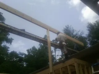 Carpenter setting a ridge beam over a new addition frame — Ice Dam Removal by Roofing Brothers in Grassy Creek