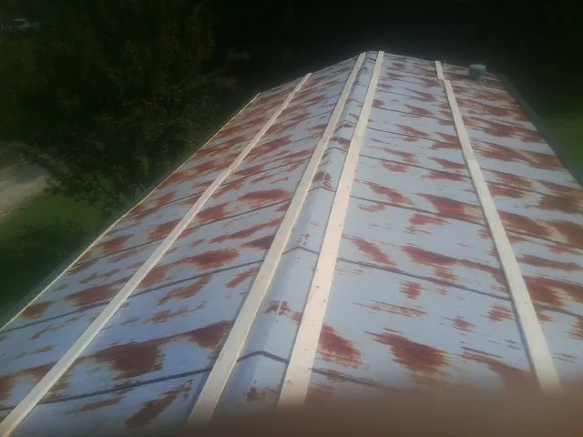 Rusted metal roof panels with new wood purlins before replacement — Storm Damage Roof Repair in Grassy Creek by Roofing Brothers