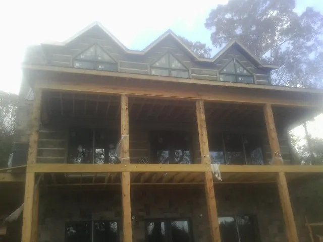 Dormers and porch framing on a large log home under construction — Roof Coating work by our crew in Grassy Creek