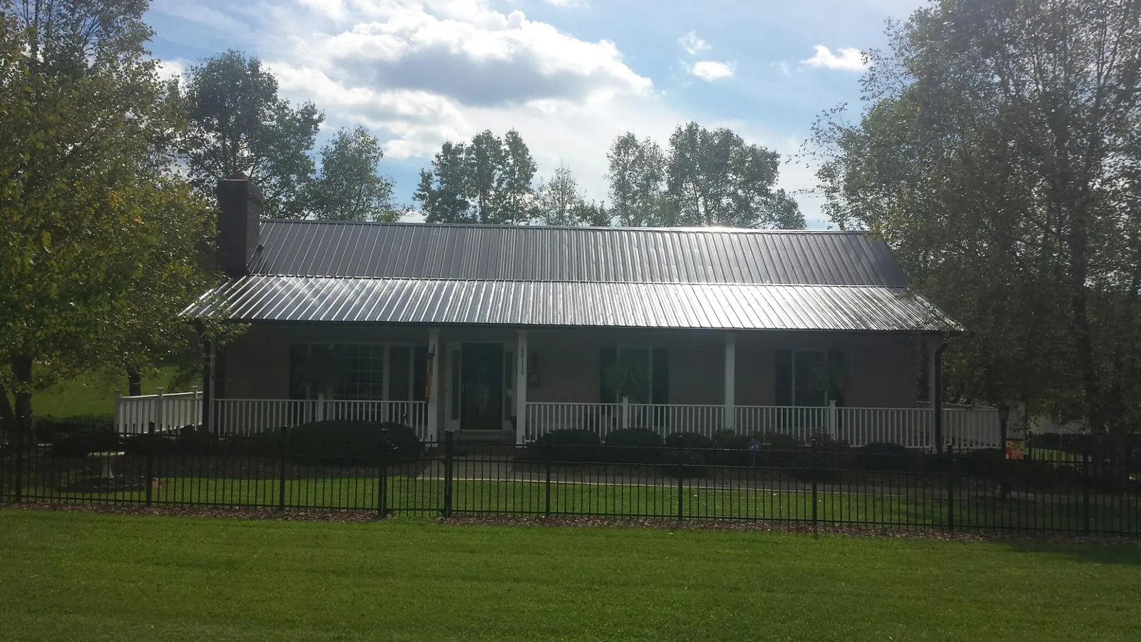 Gray metal roof on a brick ranch with a full width front porch — Gutter Guard Installation work by our crew in Grassy Creek