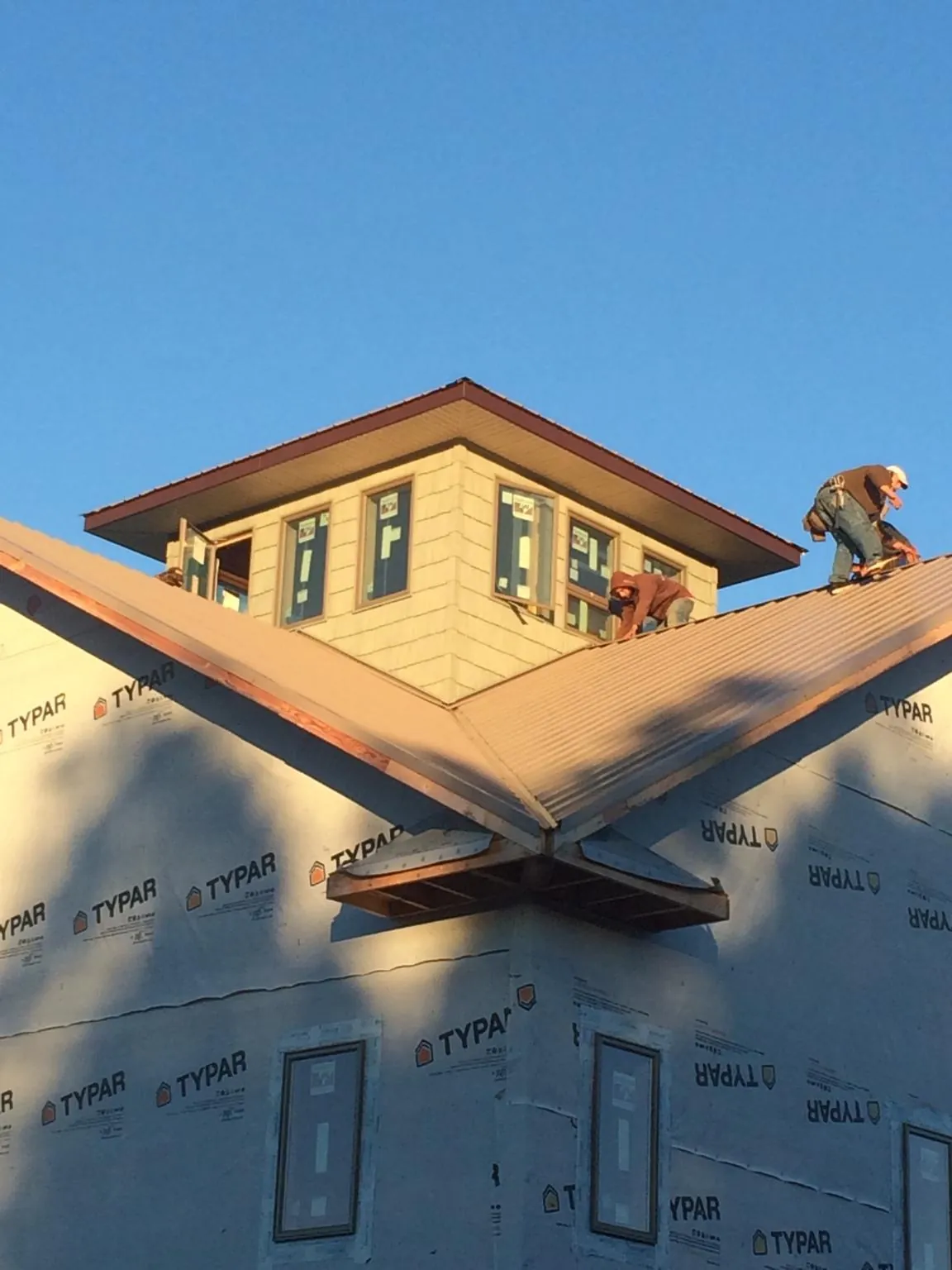 Roofers working around a rooftop cupola on a new metal roof at sunset — Roof Waterproofing in Grassy Creek by Roofing Brothers
